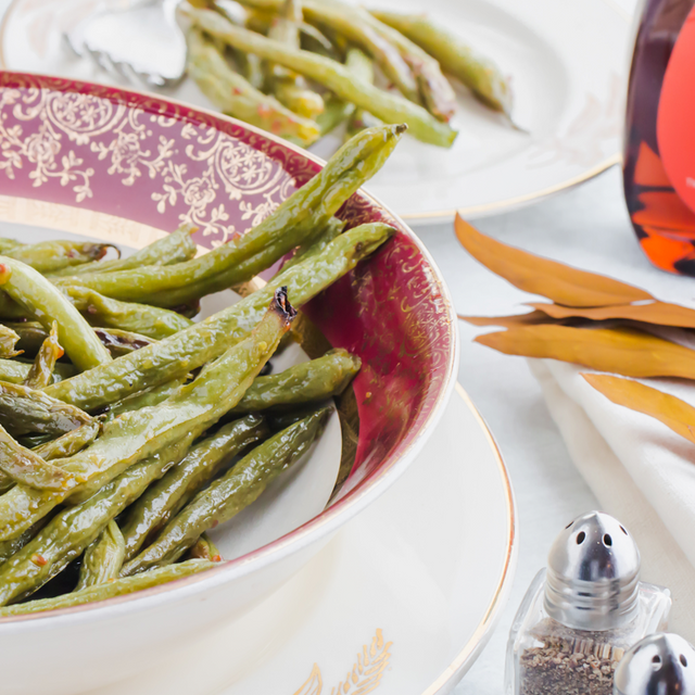 A bowl of keto green beans with a bottle of sugar free maple syrup
